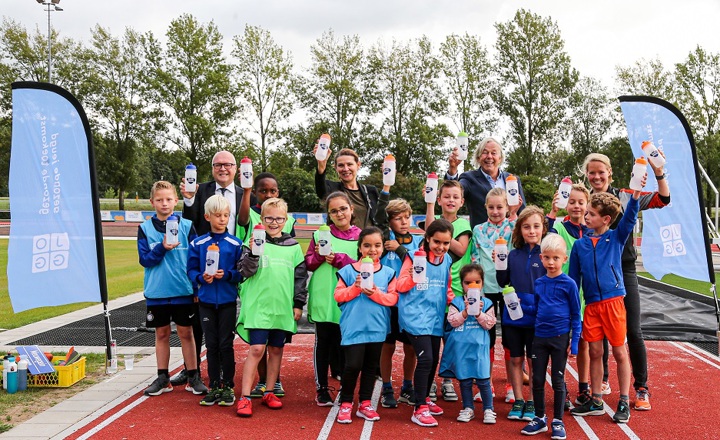 Kinderen op een atletiekbaan met een waterbidon van Joggy in hun handen
