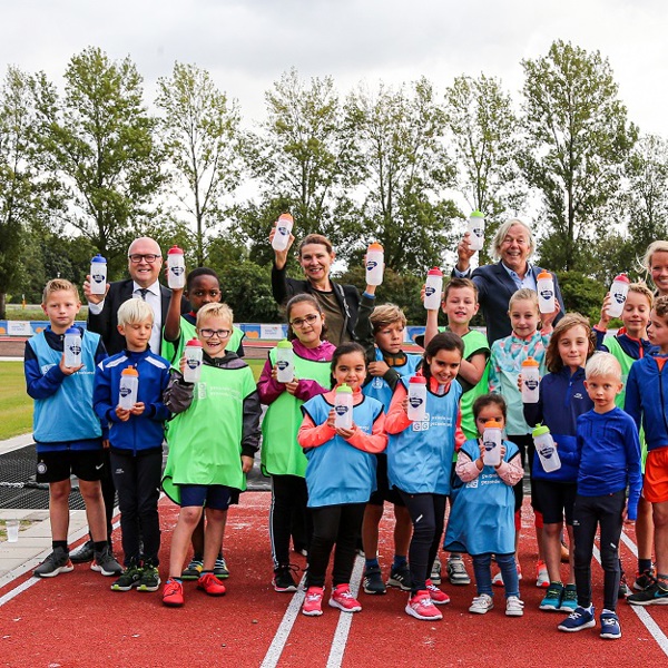 Kinderen op een atletiekbaan met een waterbidon van Joggy in hun handen