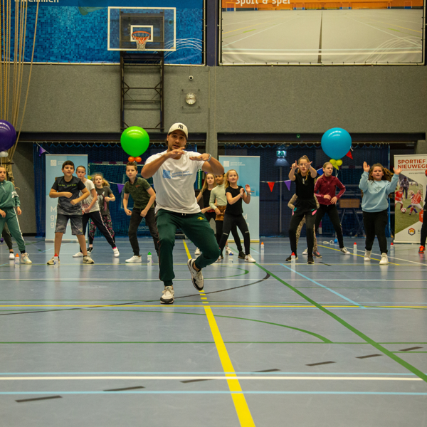 JOGG Ambassadeur Juvat Westendorp geeft een dansclinic in een sportzaal aan kinderen