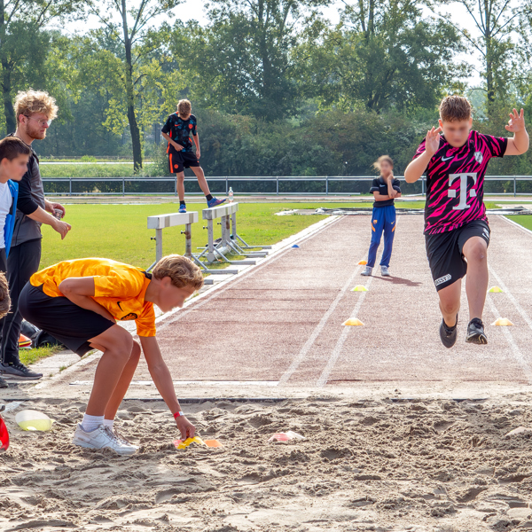 Kinderen die aan het verspringen zijn op de atletiekbaan